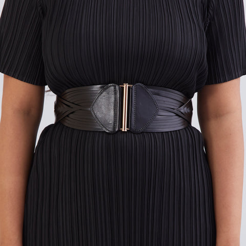 Woman in black co-ord, front view, pleated pants Woman in black co-ord, front view, pleated pants